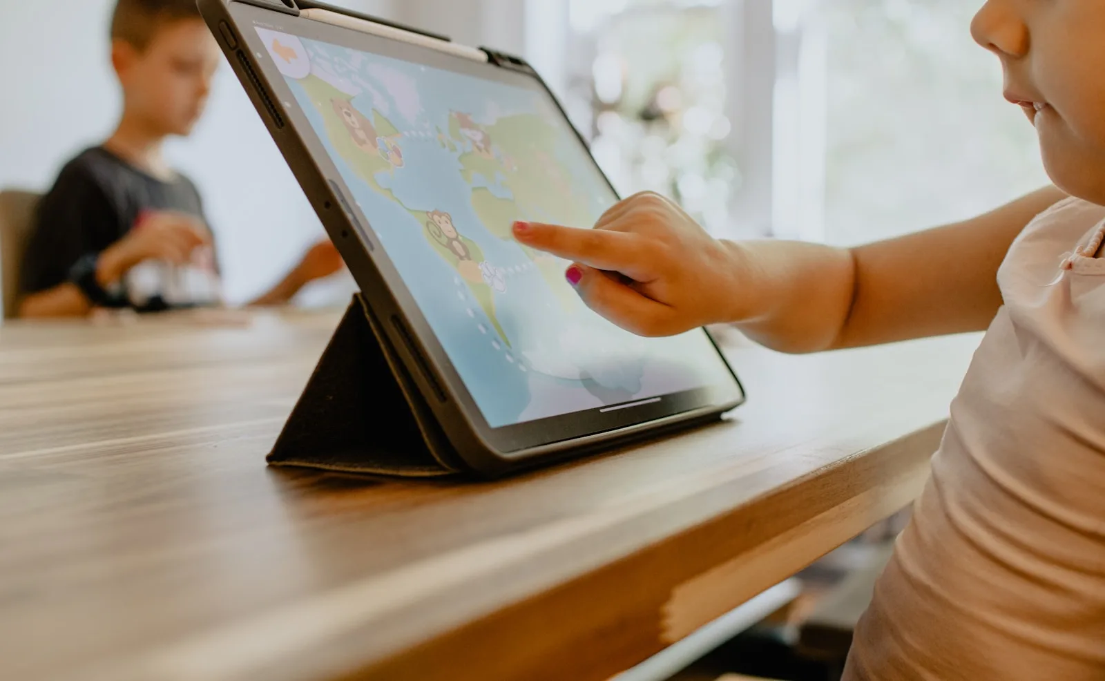 A young student writing code on a tablet at a sunlit workbench