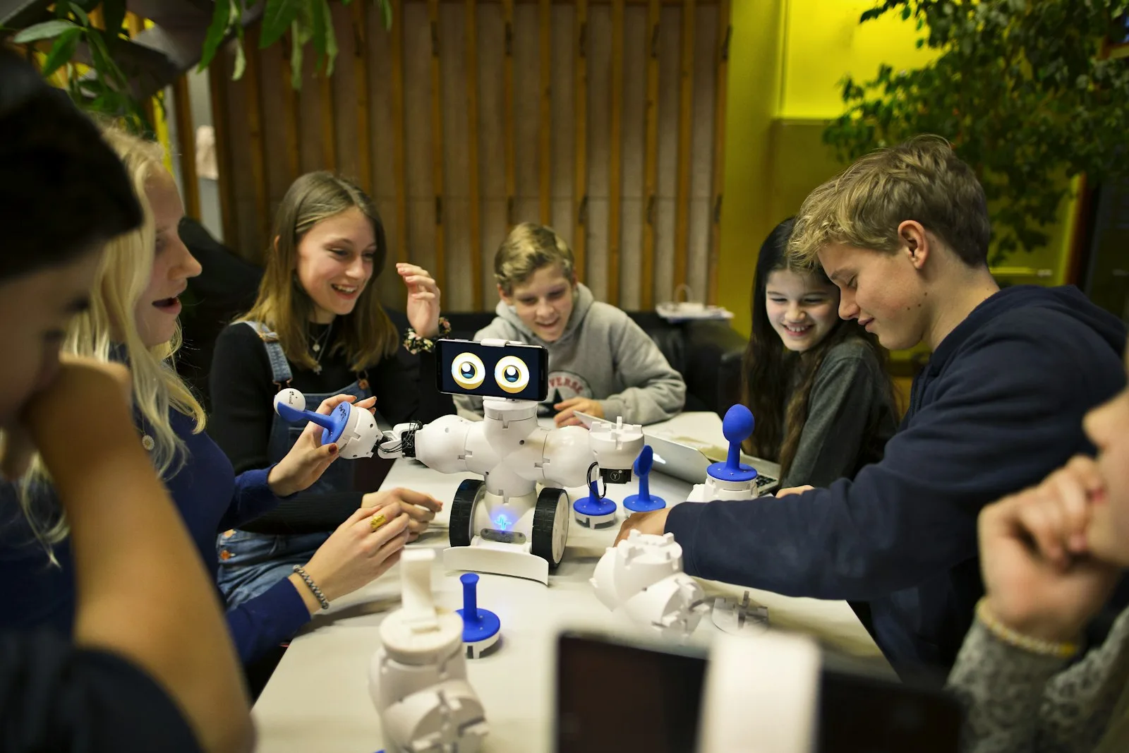 A cohort of students laughing together around a robot they built and programmed