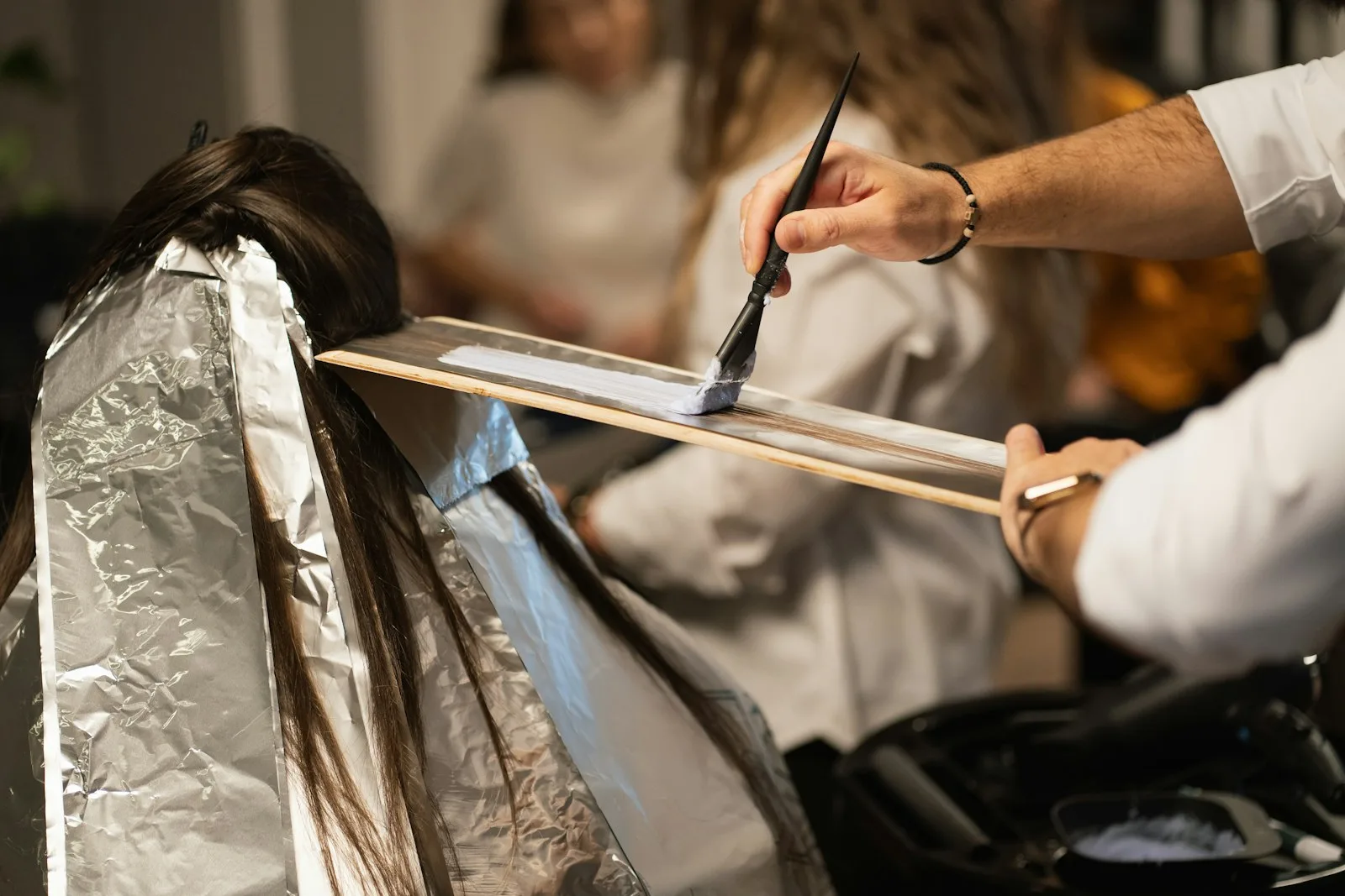 A colorist painting lightener along a foiled section at the board.