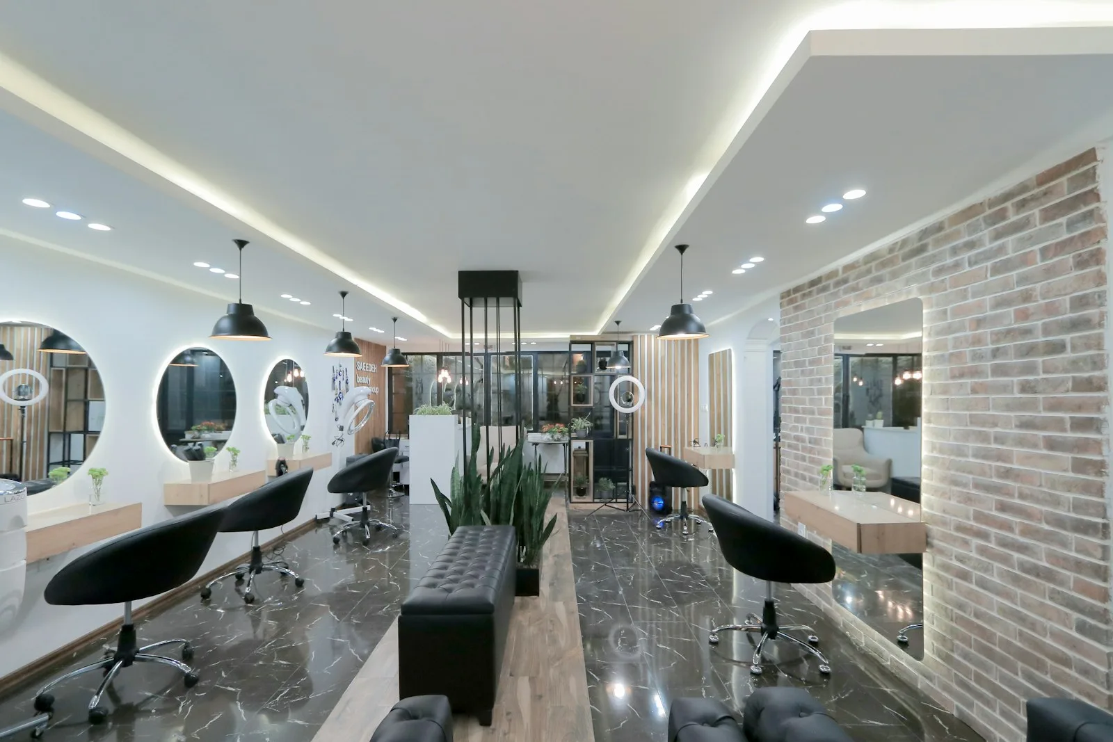 The Saffron atelier floor, round lit mirrors along a brick accent wall.